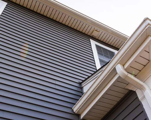 Gray horizontal vinyl siding on home exterior with white trim and gutter