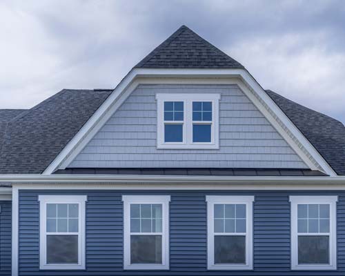 Blue home exterior with white double-hung windows and gray shingle siding on dormer